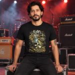 Hombre con playera negra de Korn frente a equipo de escenario