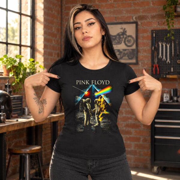 Mujer con playera negra Pink Floyd de astronautas y arcoíris señalando el estampado