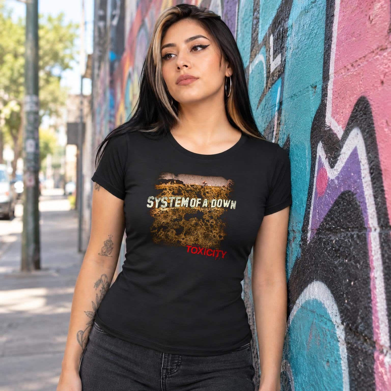 Modelo con playera negra corte dama de Toxicity en calle con grafiti
