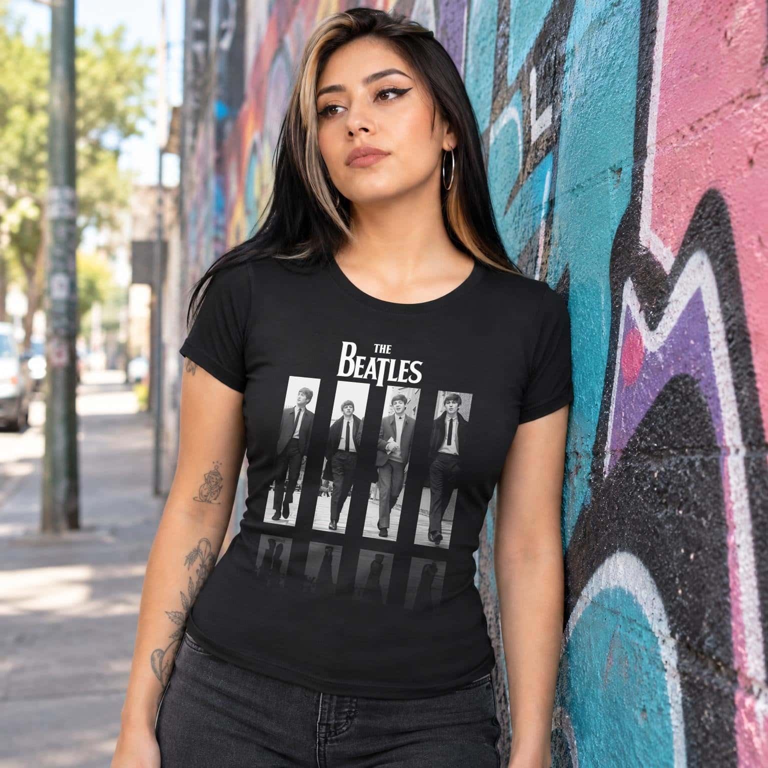 Modelo con playera negra corte dama de The Beatles en calle con grafiti