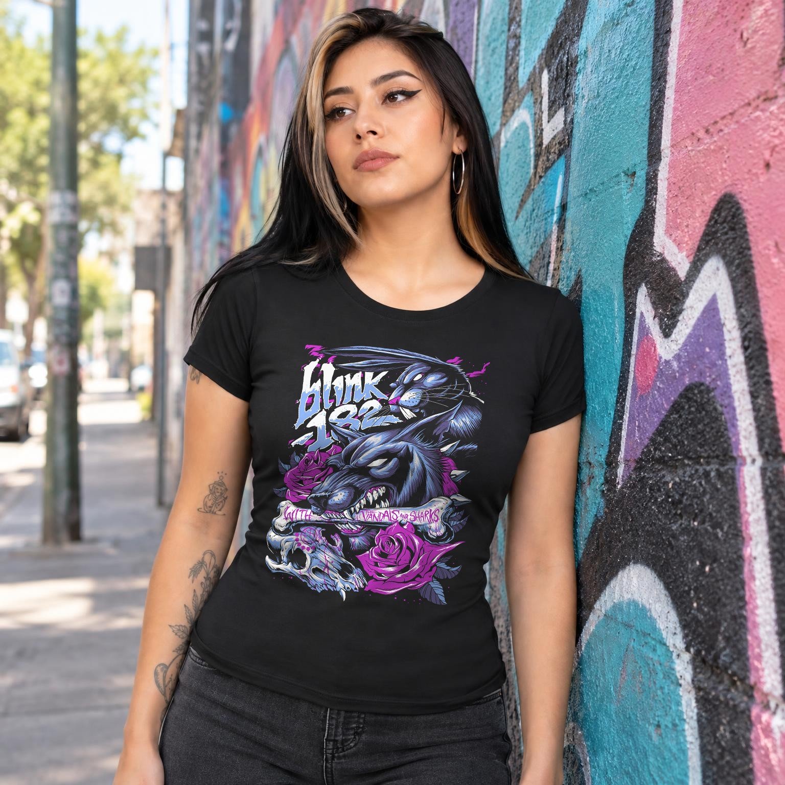 Modelo con playera negra corte dama de Blink 182 en calle con grafiti