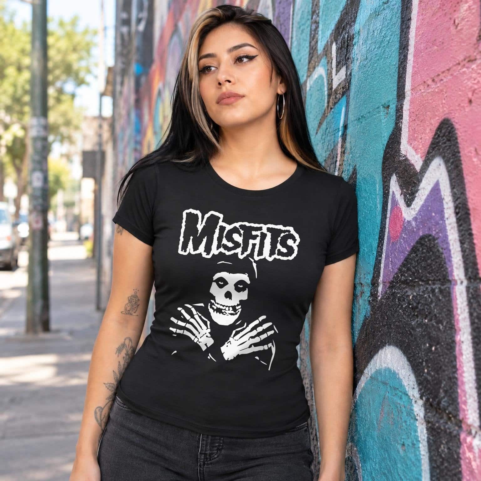 Modelo con playera negra corte dama de Misfits en calle con grafiti