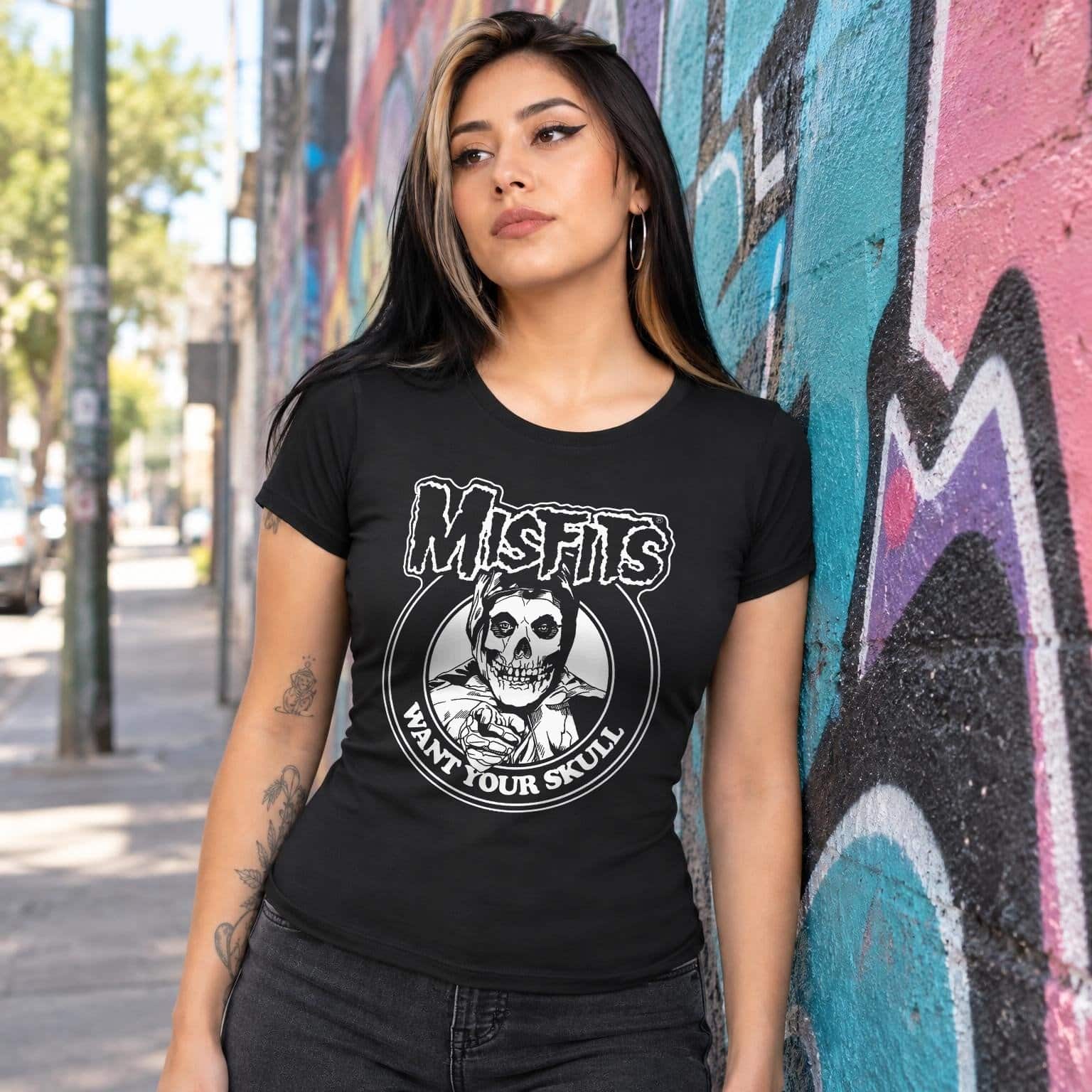 Modelo con playera negra corte dama de Misfits en calle con grafiti